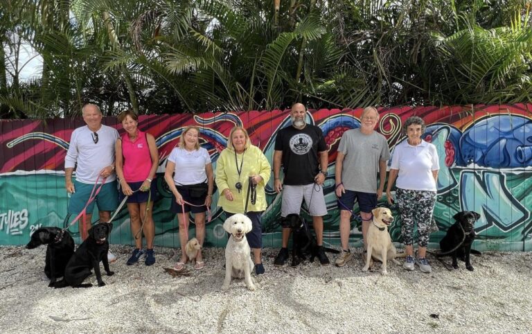 Group of people with dogs in front of graffiti wall.